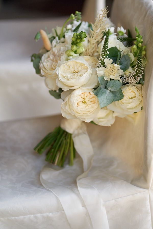Bridal bouquet with creamy white garden roses, eucalyptus and greenery on a chair in Prague
