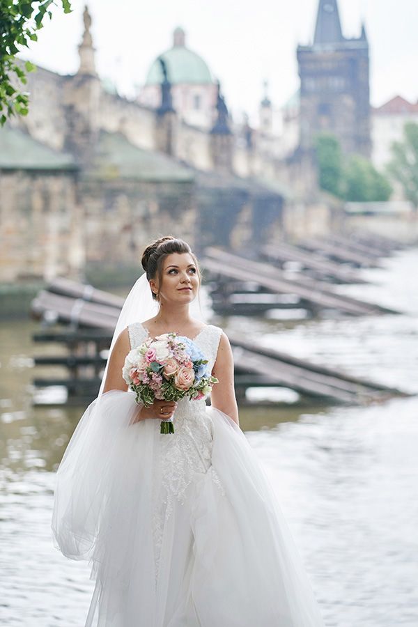 Bride with pastel wedding bouquet near Charles Bridge in Prague | Невеста с нежным букетом у Карлова моста в Праге | Наречена з весільним букетом у пастельних тонах біля Карлова мосту в Празі | Nevěsta s jemnou svatební kyticí u Karlova mostu v Praze