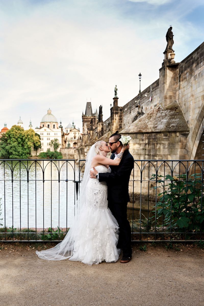 Couple kissing with the famous Charles Bridge in the background in the Czech Republic.